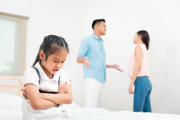 家庭问题：孩子在父母争吵的背景下。悲伤的小女孩在卧室里不快乐，哭泣，反对父母在家争吵，或家庭中发生冲突图片下载
