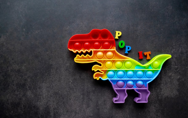 玩具pop it恐龙彩虹颜色在黑色背景上与多种颜色的字母和题词- pop it on the back。本空间图片下载