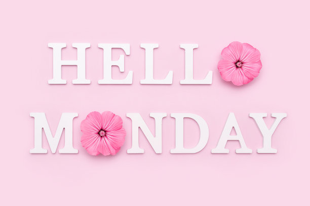 黑色的字板上写着快乐的星期一，蓝色木墙旁的桌子上放着一束装在锡罐花瓶里的鲜艳的野花。你好,周一概念图片下载