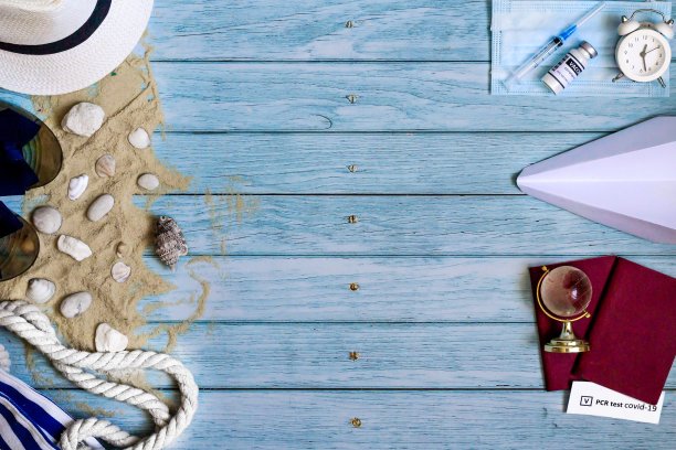 2019冠状病毒病大流行期间的旅行理念。在蓝色木制背景上平铺复制空间。夏日海滩度假的配件，预防冠状病毒的主要方法:接种疫苗和PCR检测图片下载