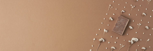 棕色背景上的肥皂和花。平铺，复制空间。图片下载