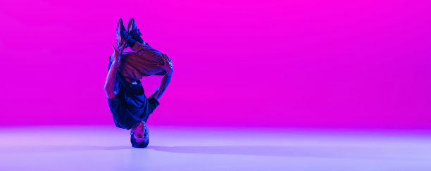 在霓虹灯下的舞厅里，年轻男子的肖像，霹雳舞舞者穿着现代服装，在明亮的紫红色背景下独自跳舞。图片下载