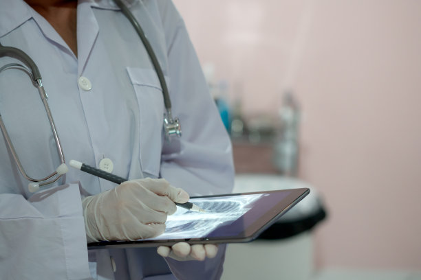 特写女医生在手术室的照片，亚洲女性穿着白色制服在剪报上看，白色的东西上。图片下载