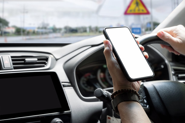 男子开车时手持空白屏幕的智能手机。图片下载