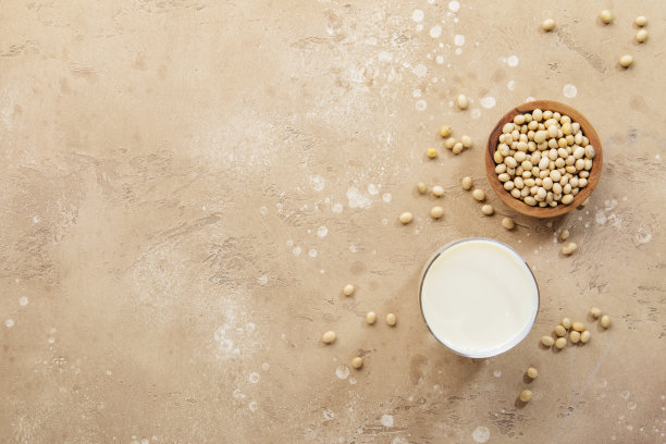 米色桌子上的豆浆和大豆。素食饮料。负空间图片下载