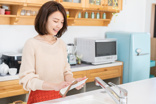 漂亮的亚洲女人在厨房里洗盘子图片下载