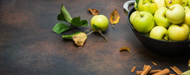 生的水果。新鲜的苹果果实。花园绿苹果和中国桂枝在生锈的深棕色桌子上。带有复制空间的长水平横幅图片下载
