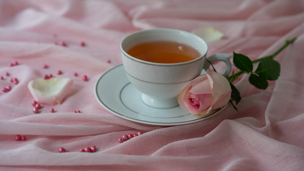 一杯茶和一束粉红色背景上的玫瑰。图片下载