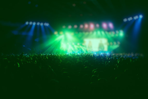 拥挤的音乐厅现场舞台绿灯，摇滚表演表演，与人的剪影图片下载