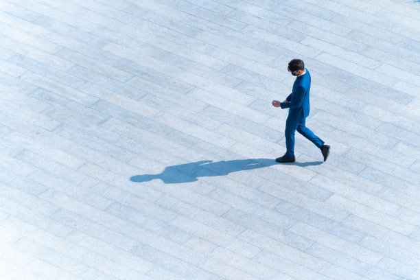 顶部鸟瞰商人们走在行人混凝土上，地面上有黑色的剪影，社会静物的概念。图片下载