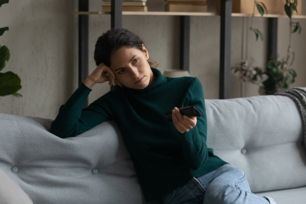 关闭无聊的女人拿着遥控器，切换频道图片下载