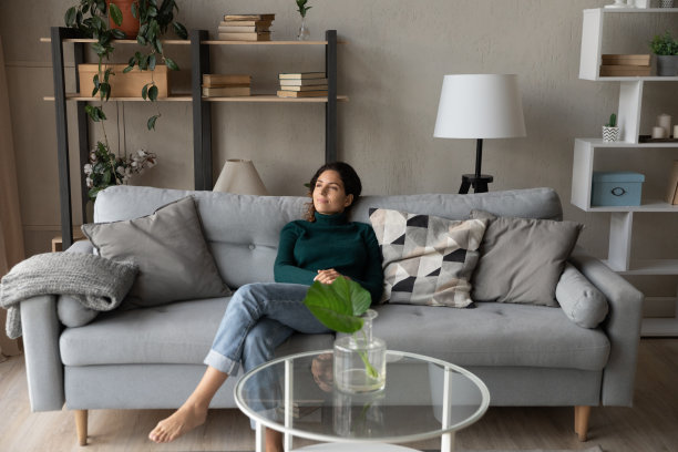 满意的女人在舒适的沙发上放松在现代客厅图片下载