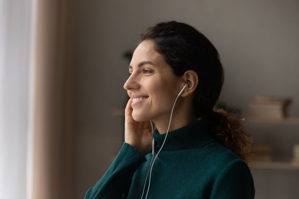 靠近正在听音乐的微笑梦幻女人的侧面图片下载