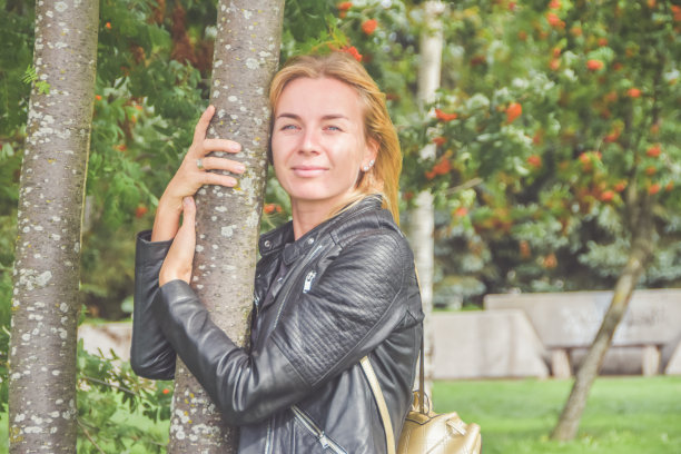 美丽的女孩拿着伞在树与花楸树之间图片下载