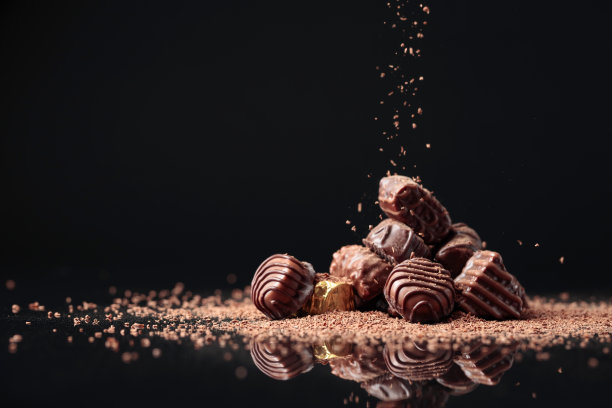 黑色背景上的巧克力糖果上撒着巧克力屑。图片下载