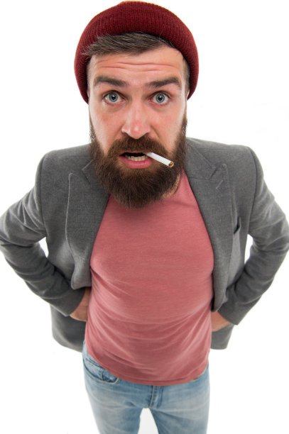 野蛮的胡子男人抽烟孤立的白色背景。残酷的习惯和生活方式。嬉皮士，留着胡子的烟鬼。一个凶残的留着胡子的嬉皮士打扮成流浪汉，抽着烟图片下载