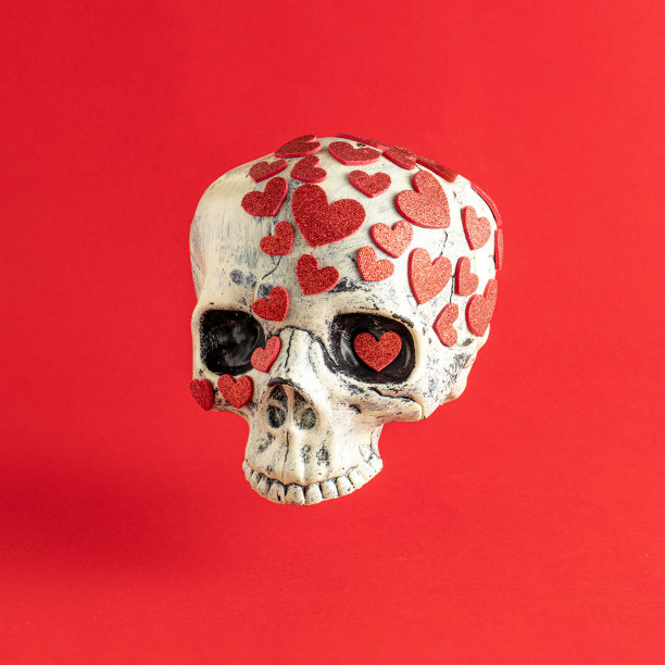 有小红心的头骨。最小的浪漫爱情概念。万圣节的创作背景。图片下载