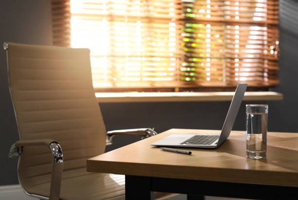 现代办公室的木桌上放着笔记本电脑和一杯水图片下载