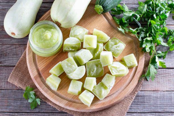 桌上的切菜板上放着冻西葫芦泥块。婴儿食品。冷冻食品的概念。图片下载