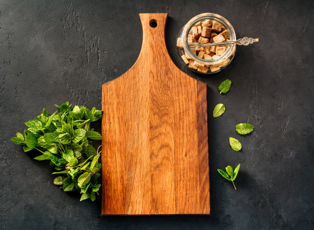 质朴的木板，新鲜的薄荷和甘蔗糖放在玻璃碗里，黑色的混凝土背景。顶视图的薄荷和木板与文本的复制空间。薄荷饮料。图片下载