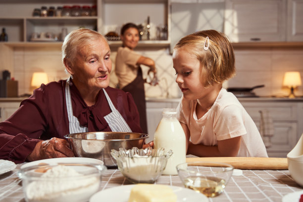 老妇人向小女孩解释烹饪过程图片下载