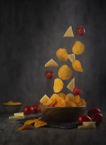 美味的薯片在碗里，奶酪，西红柿和酱汁在桌上。悬浮的食物图片下载