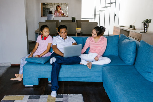拉丁美洲一个患有脑瘫的少女和她的家人坐在客厅里用电脑，在拉丁美洲残疾概念图片下载
