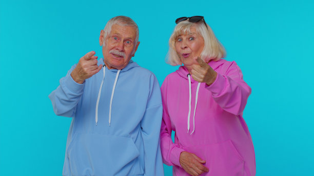 可爱的成熟夫妇男人女人祖父母指着镜头，大声大笑，有趣的笑话图片下载