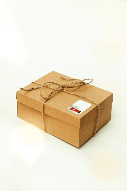 用黄麻线系着的硬纸板做的礼品盒，由花环灯泡发出耀眼的光，孤立在明亮的背景上。图片下载