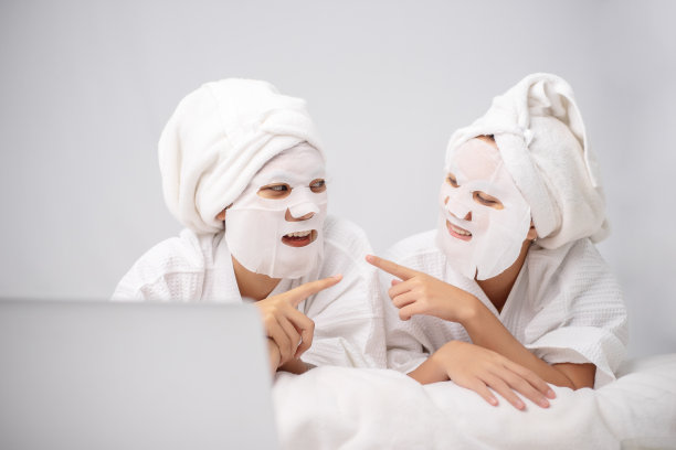 一名年轻女子一边用毛巾包着头发，一边享受着自制的面膜。美容治疗衰老返老还童的过程。皮肤恢复美白，保湿，亮肤。图片下载