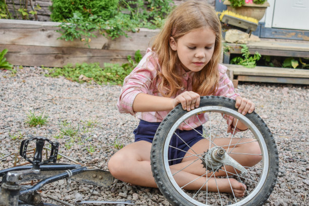 一个小女孩损坏了一个自行车轮子，正在修理照片没有处理图片下载