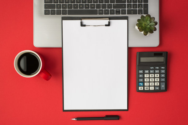 顶部视图的照片，在笔记本电脑上的花盆，杯子，饮料，钢笔，计算器和黑色的剪贴板文件夹与白色的纸页在孤立的红色背景与空白图片下载