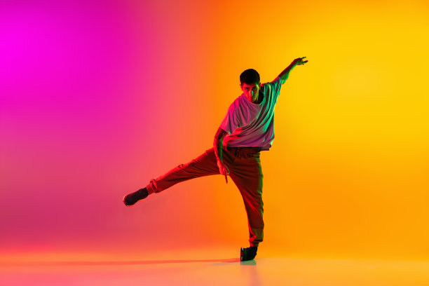 年轻时尚男人的肖像，霹雳舞舞者在霓虹灯下，在渐变的粉红色背景下孤立的休闲服装训练。图片下载