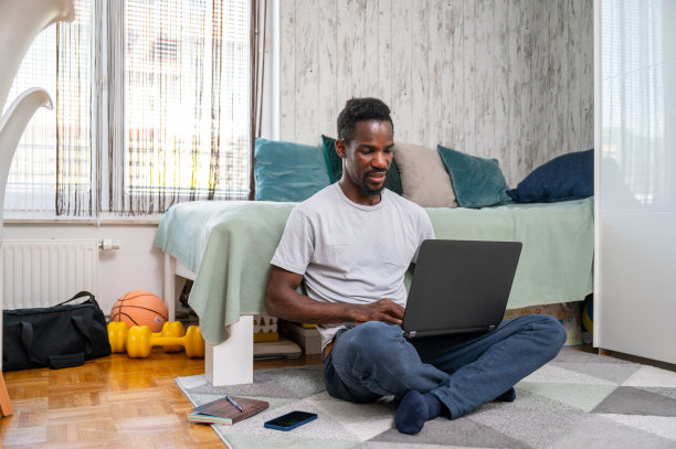 一个年轻人坐在地板上用笔记本电脑图片下载