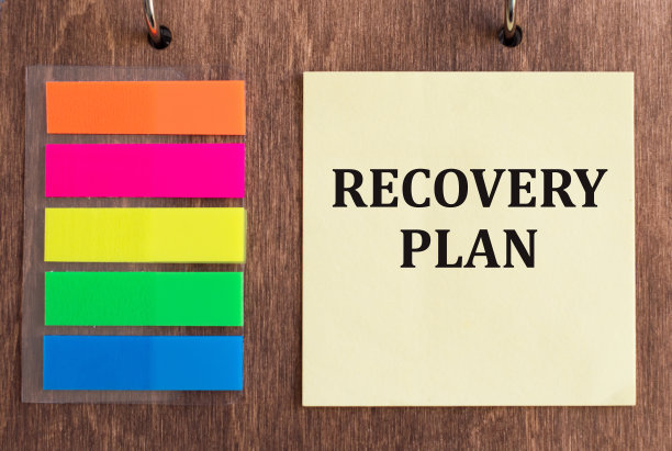 木制背景的黄色便条卡上印有“恢复计划”字样。一个业务概念。图片下载