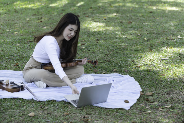 美丽的亚洲女子手持小提琴在自然的背景下，在情感快乐的感觉。图片下载