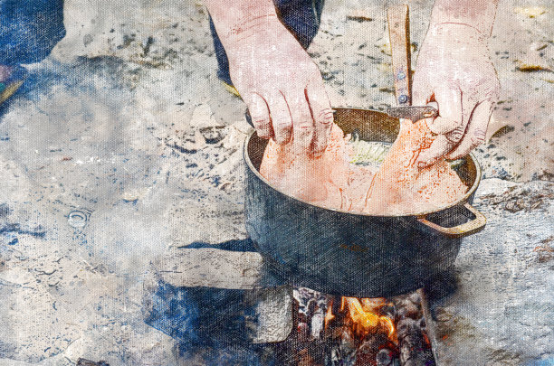 一个人在火上煮鱼汤。把手伸进锅里图片下载