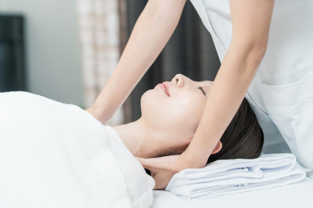 在美容沙龙按摩头部的年轻女子图片下载