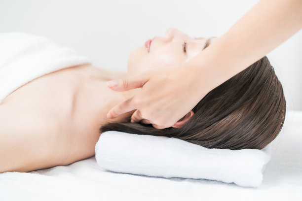 在美容沙龙按摩头部的年轻女子图片下载