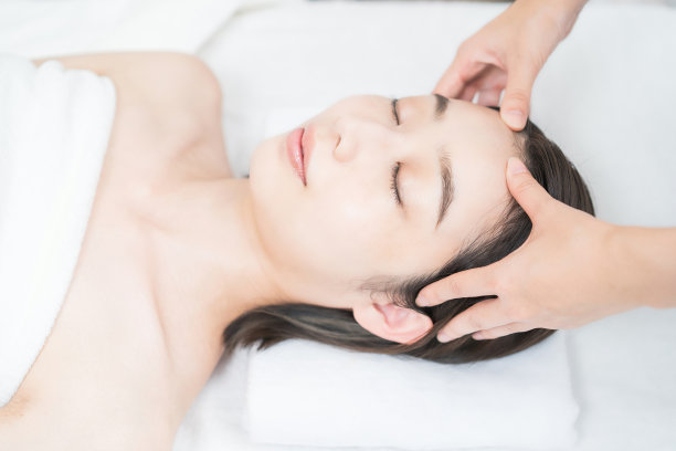在美容沙龙按摩头部的年轻女子图片下载