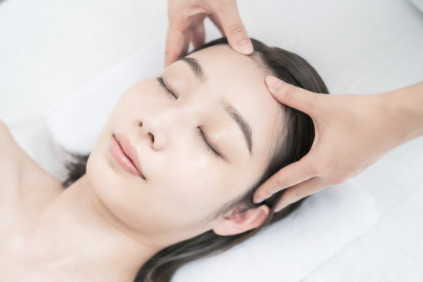 在美容沙龙按摩头部的年轻女子图片下载