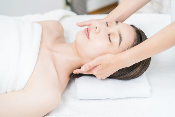 在美容沙龙按摩头部的年轻女子图片下载