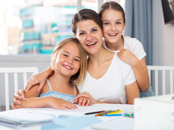 快乐的女孩和妈妈一起在桌子旁画画图片下载