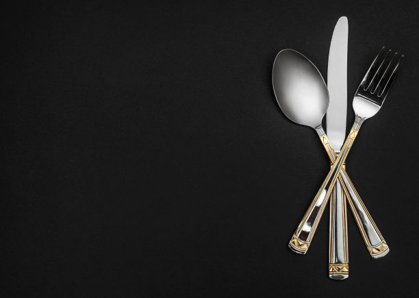 叉子、刀和勺子放在黑色背景上。前视图。空间的文本。图片下载