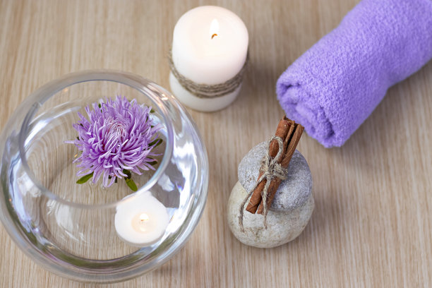 俯视图水疗背景。一堆石头，上面有肉桂棒，一朵丁香花，一条卷着蜡烛的毛巾图片下载