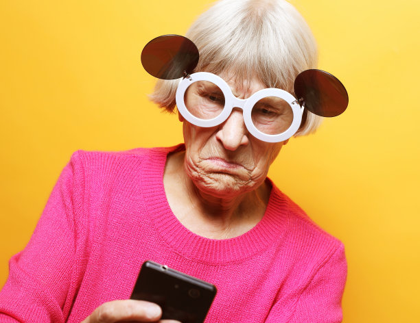 老祖母在电话里和她的孙子们聊天，微笑着和他们打招呼。图片下载