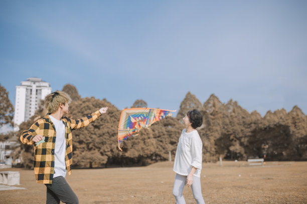 一个亚洲华人少年和他的祖母在一个阳光明媚的早晨在公园里玩风筝图片下载