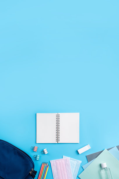 蓝色背包与文具在蓝色的桌子背景。图片下载
