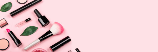 各种化妆品配件的化妆和美甲在时尚的淡粉色背景。腮红，刷子，眼影，睫毛膏，香水，口红，指甲油。皮肤护理产品。副本的空间。横幅。图片下载
