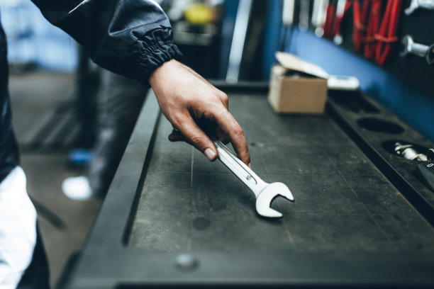 陌生人，一名男工人从墙上拿工具修理自行车或汽车。图片下载